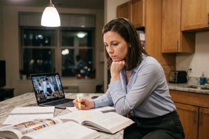 Femme adulte étudiant un manuel de cuisine chez elle le soir pour préparer son CAP cuisine en reconversion professionnelle